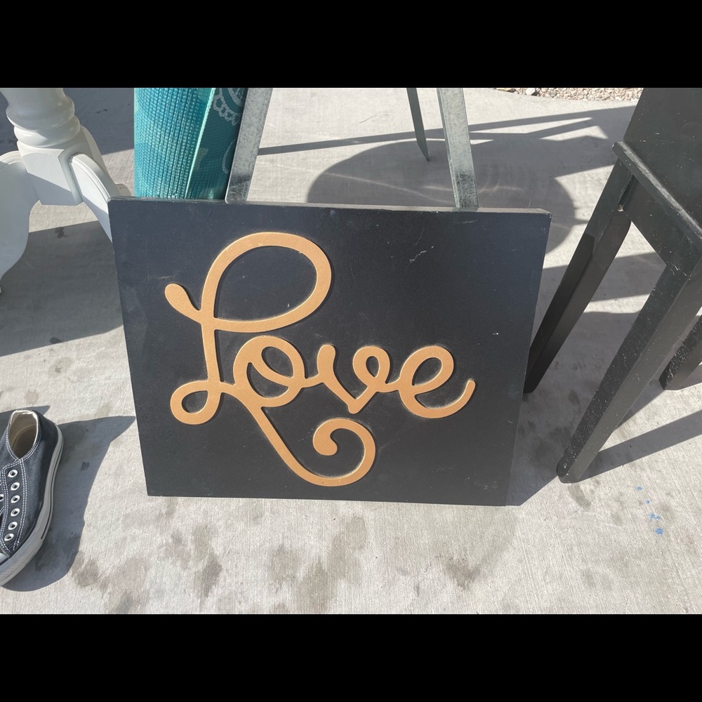 Black sign with gold love written on it